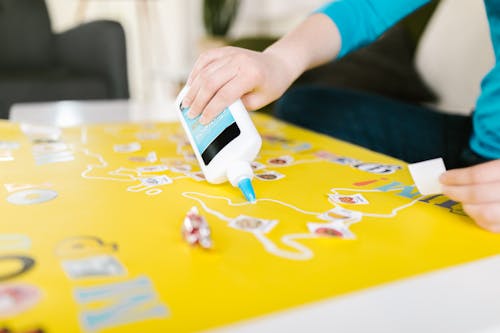 A Person Using a Glue over Yellow Paper