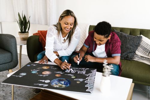 Free A woman and a boy working on a creative solar system project indoors. Stock Photo