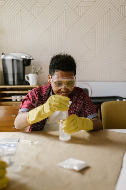 A child conducting a science experiment with concentration, wearing protective gear indoors.
