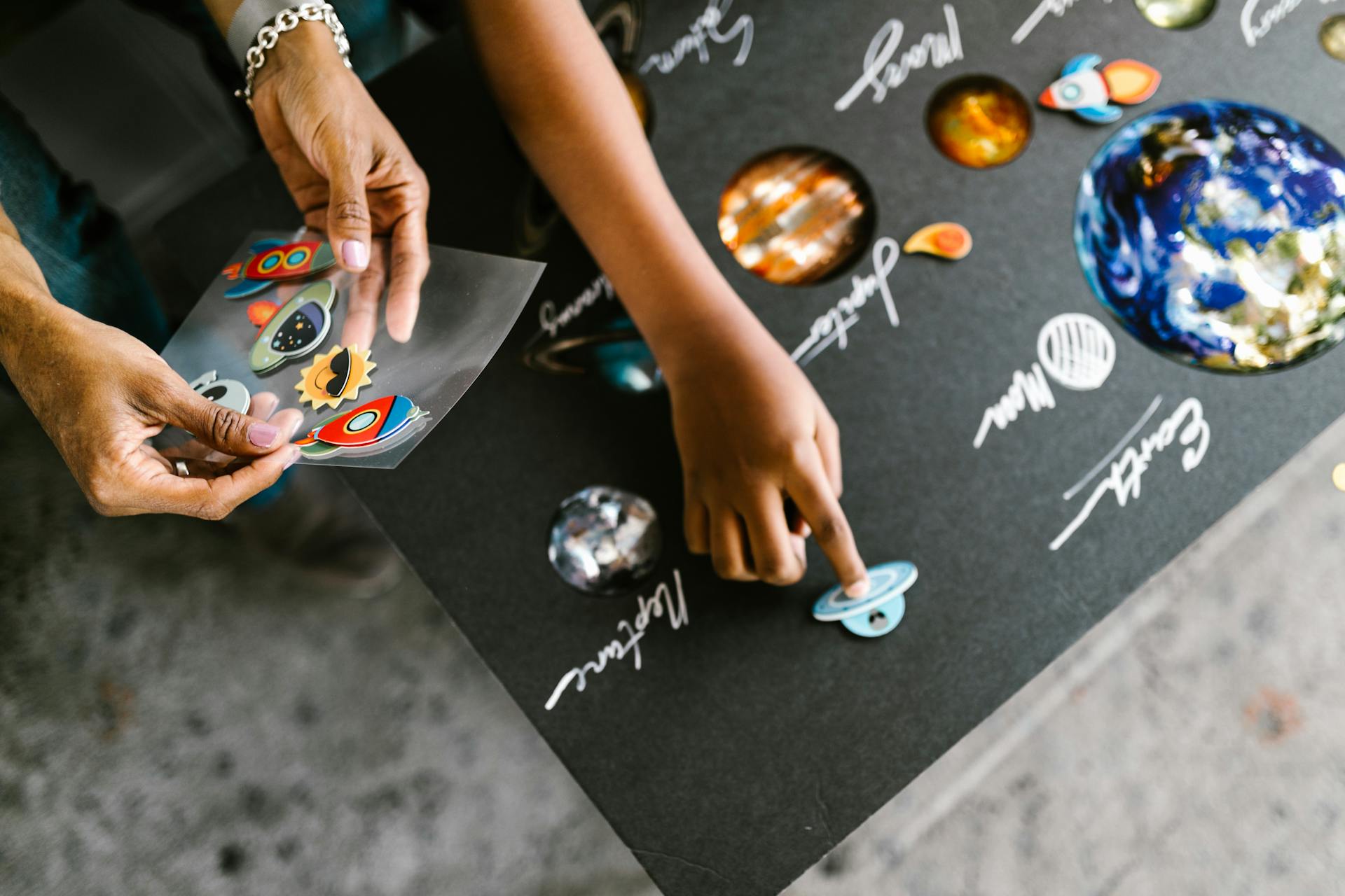 Hand of a Child Putting Stickers on a Gray Board