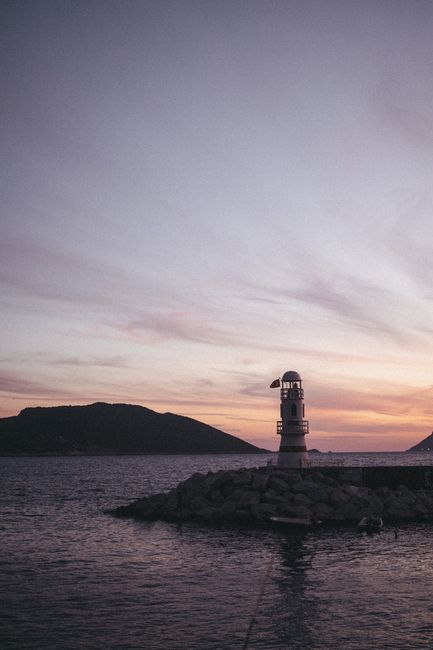A serene lighthouse by the sea at twilight with colorful skies and tranquil waters.