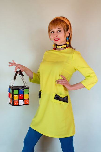 Fotomural Retrato de moda vibrante de una mujer en un vestido amarillo sosteniendo un bolso en forma de cubo.