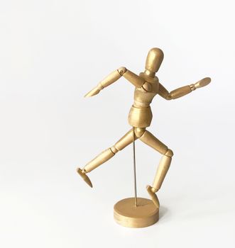 A gold-painted wooden mannequin posing creatively against a white background.