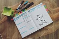 木桌上摊开着手写笔记和彩色笔标注的计划书，用以激发积极情绪