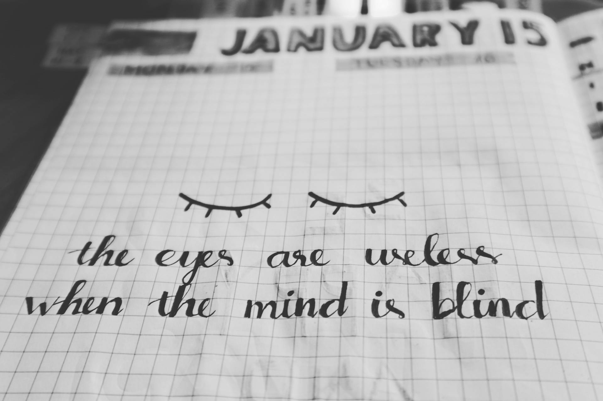 Black and white notebook page with an inspirational quote and eye illustration on a grid background.