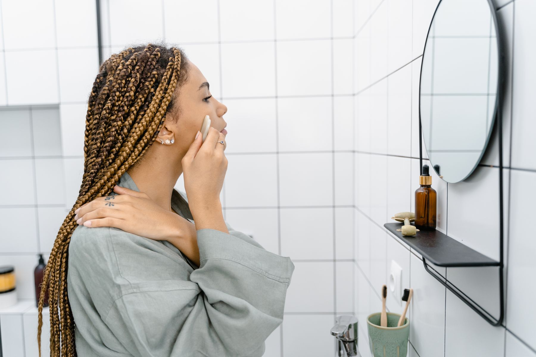 Woman applying a personal care product while looking in a bathroom mirror during a calm daily routine