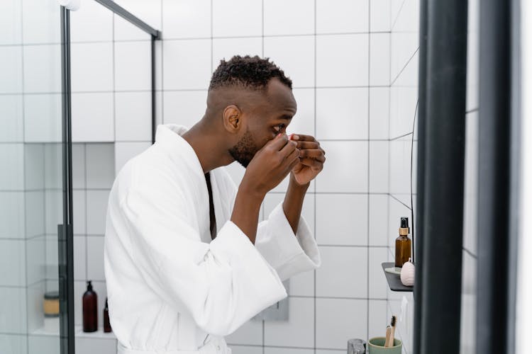 A Man In A White Bathrobe In A Bathroom