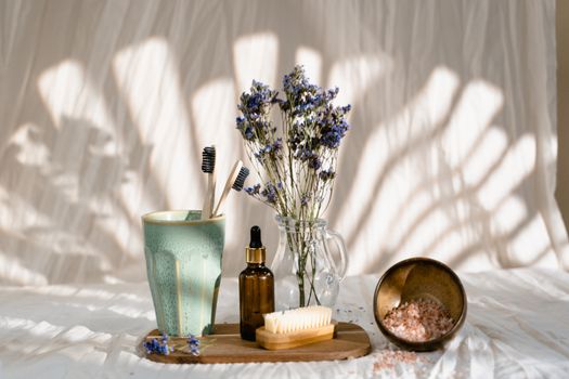 Stylish self-care arrangement with toothbrushes, essential oil, and dried flowers.