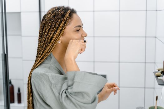 A woman with braided hair brushing her teeth, emphasizing daily oral hygiene and self-care.