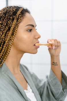 Side view of a woman brushing her teeth, embracing hygiene and self-care.