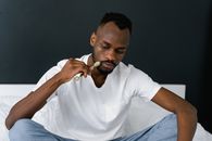 Man in White Crew Neck T-shirt and Blue Denim Jeans Sitting on Blue Textile