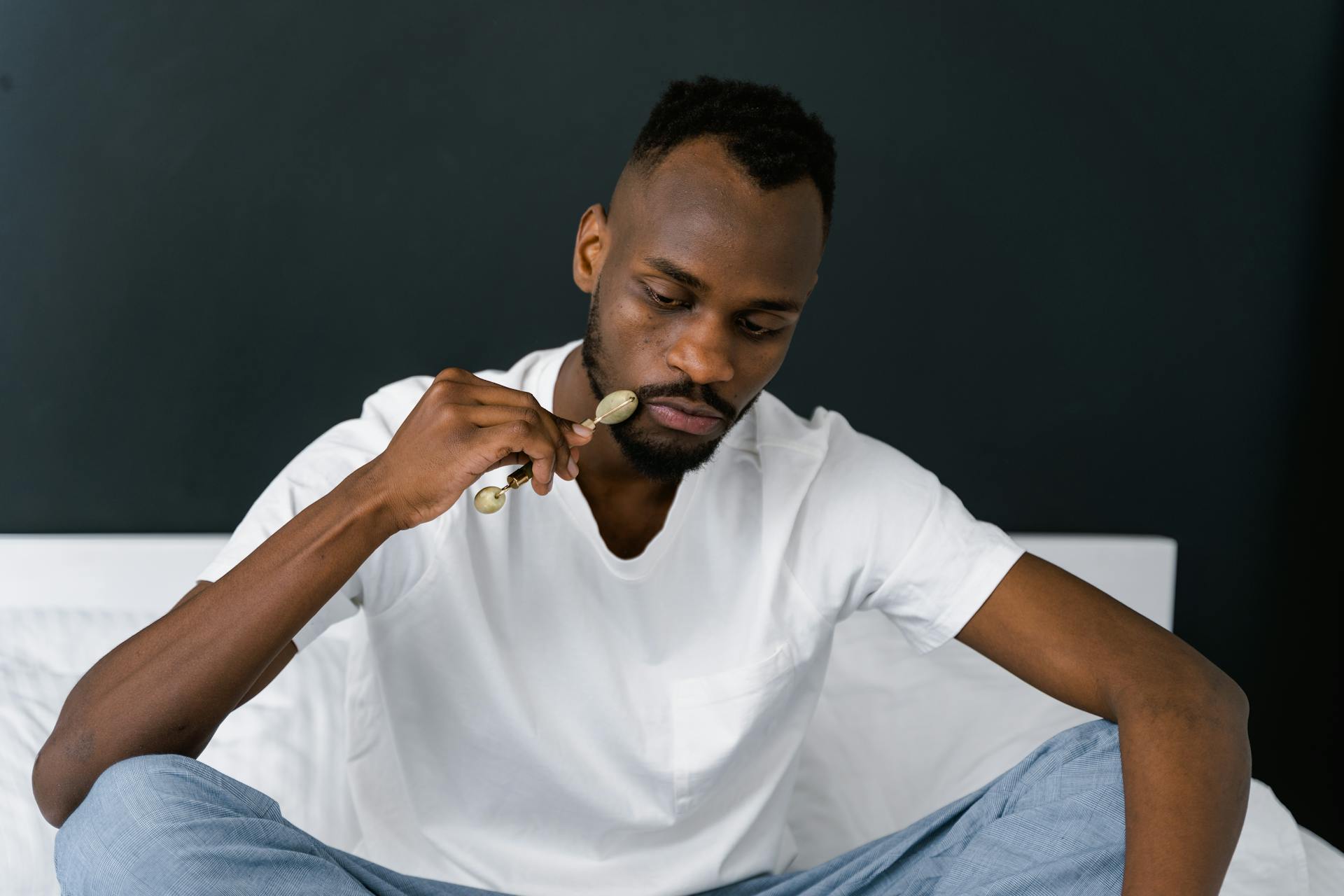 A man using a jade roller for facial care, promoting skincare routines.