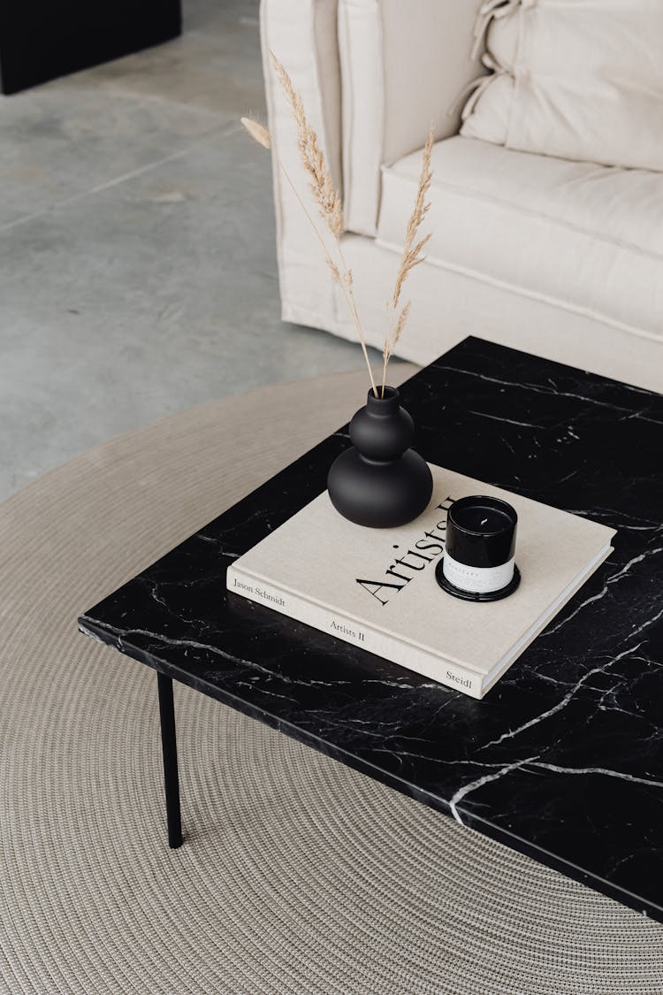 Candle And Small Vase Standing On Book On Black Table