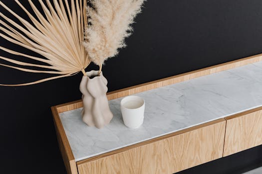 Elegant minimalist decor featuring a vase with pampas grass on marble-top furniture.