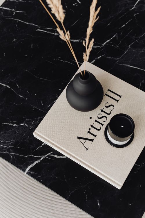 Free Flat lay of a black vase and minimalist book titled 'Artists II' on a marble surface, modern decor. Stock Photo