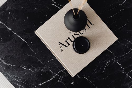 Free Top view of minimalist decor with a vase and book on a black marble table surface. Stock Photo