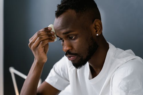 A Bearded Man in White Shirt Doing His Skin Care