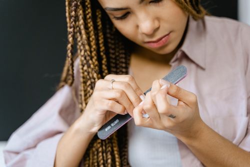 Free Young woman focusing on self-care, filing her nails for a grooming routine. Stock Photo
