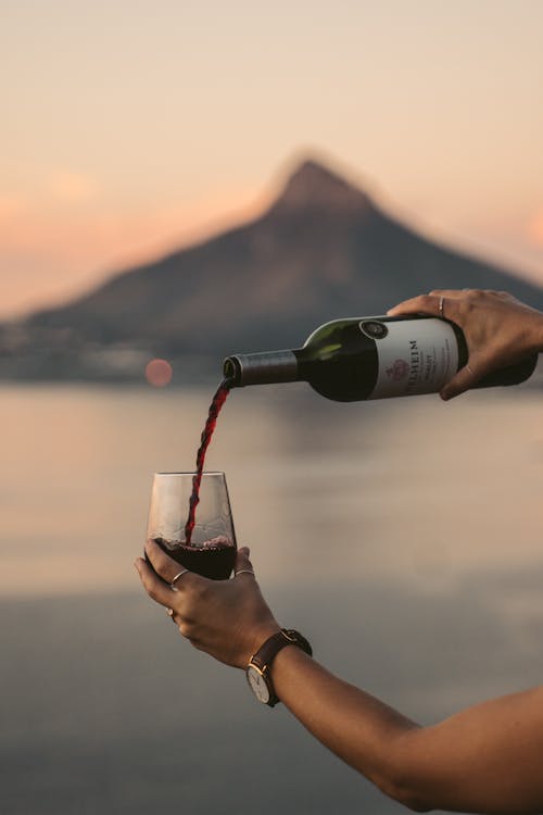 A Person Pouring a Red Wine on a Clear Glass