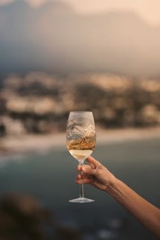 Raise a glass of white wine against a picturesque coastal backdrop, perfect for celebrations.