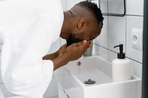 Man in White Bathrobe Washing His Face