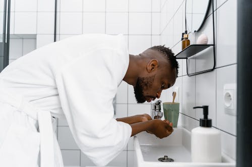 A Man Washing his Face on the  Bathroom Sink