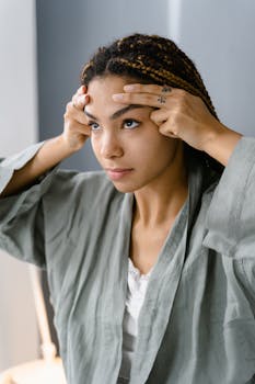 Young woman doing facial massage, promoting relaxation and skin care routine, indoors.