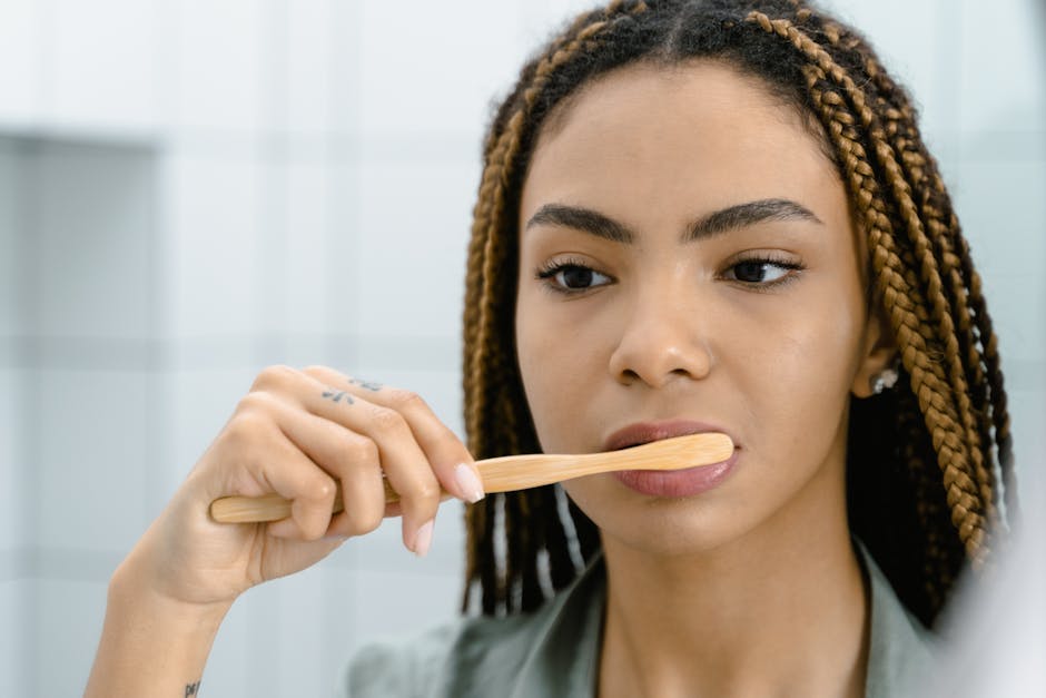 Close-up of a woman with braided hair brushing her teeth, highlighting oral hygiene.