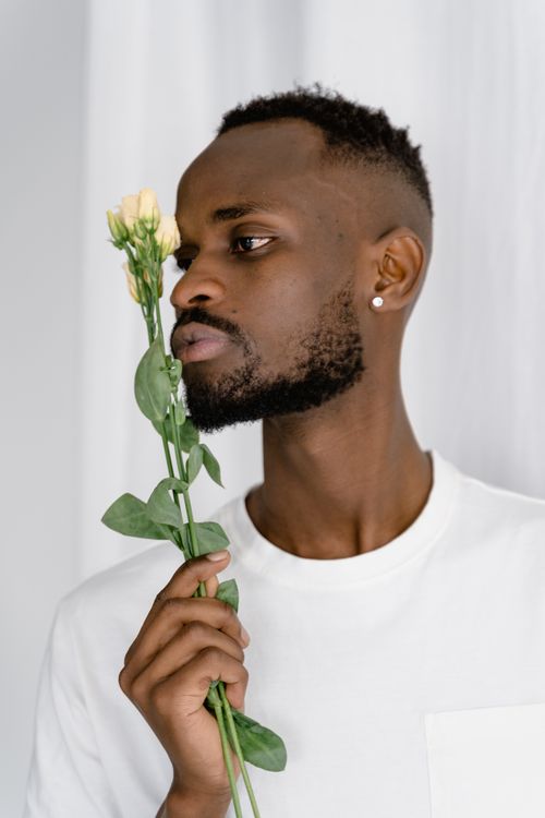 Free Close-up portrait of a man in a white shirt holding yellow flowers indoors. Stock Photo