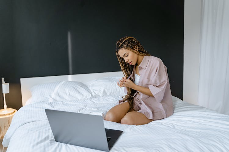 
A Woman Filing Her Fingernails In Bed