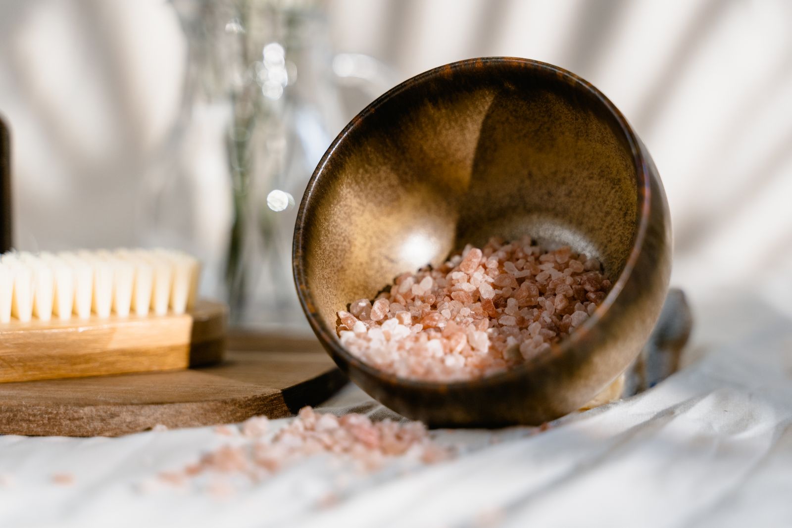 Pink salt in a wooden bowl with a natural bristle brush