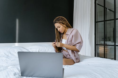 Free A Woman Sitting on Her Bed while Filing Her Fingernails Stock Photo