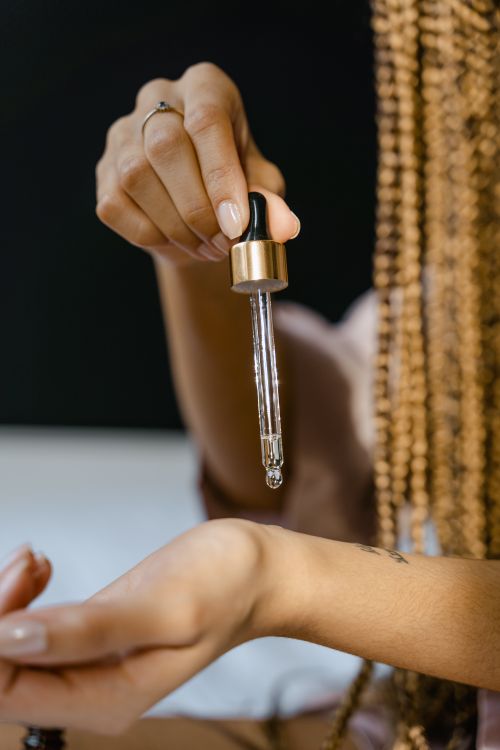Free A hand using a serum dropper to dispense liquid onto the skin, showcasing skincare routine. Stock Photo