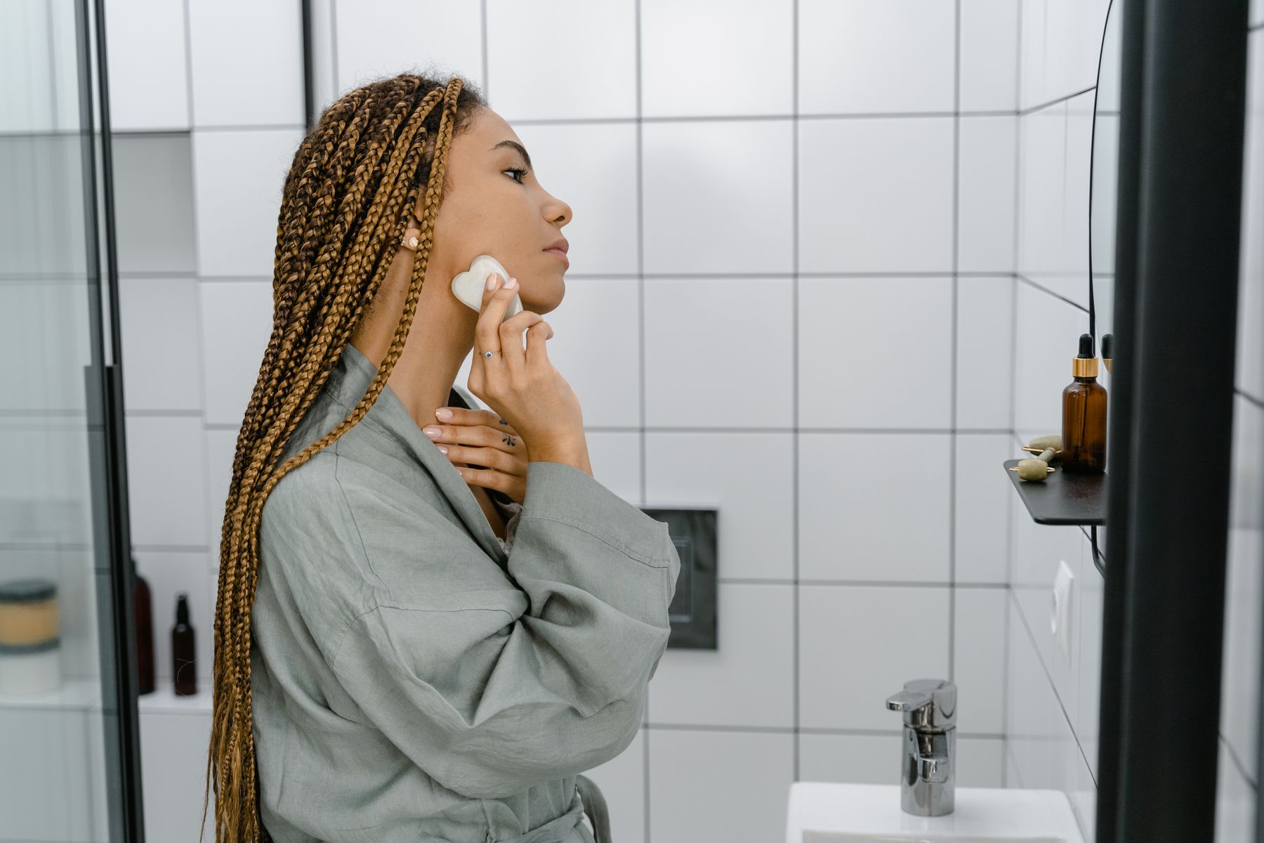 Beauty care products arranged beside a woman at a clean vanity
