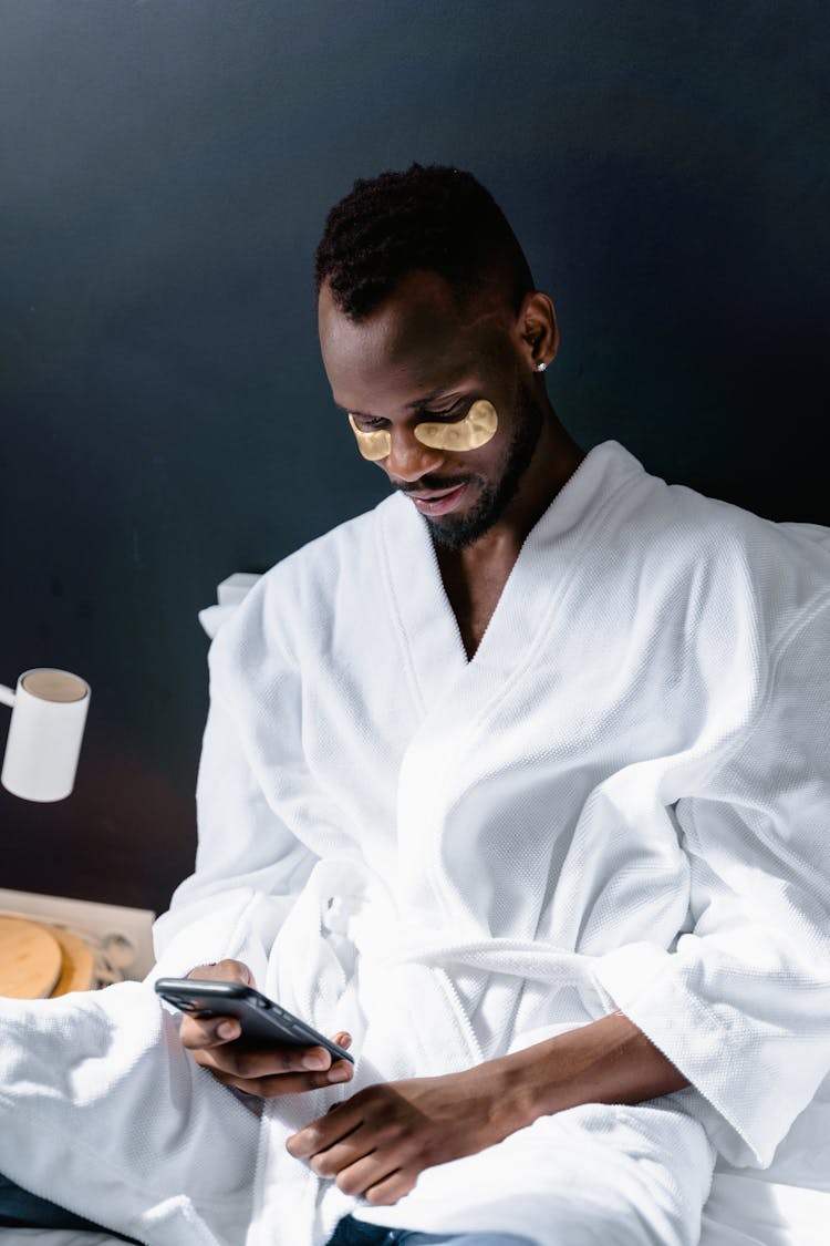 Man In White Robe Using An IPhone