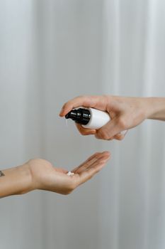 Hands applying lotion from a pump bottle, emphasizing skincare routine.