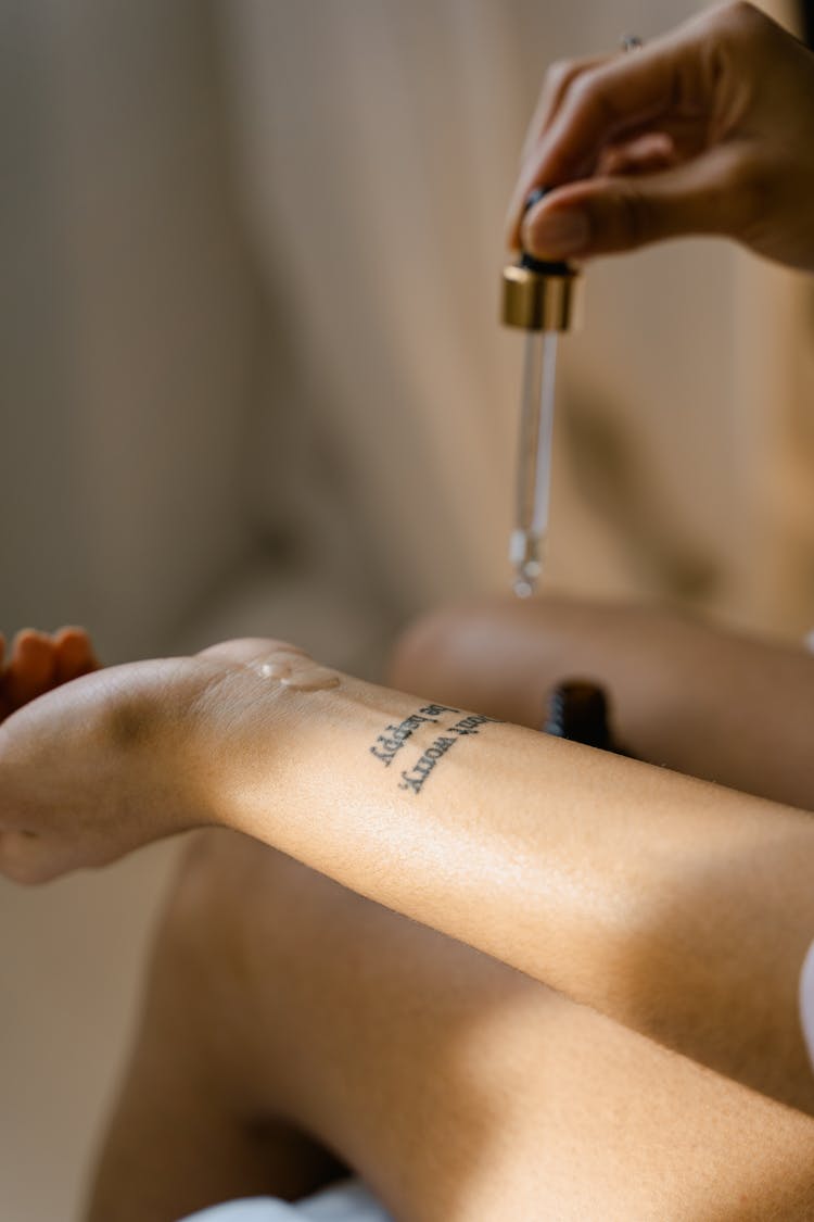 A Person Applying Oil Using A Dropper Pipette