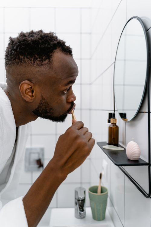 Free Side view of a man brushing teeth in bathroom, self-care routine. Stock Photo