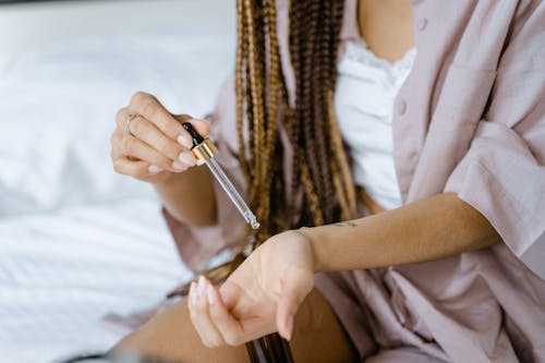 Free A Woman Applying Oil on Her Wrist Stock Photo