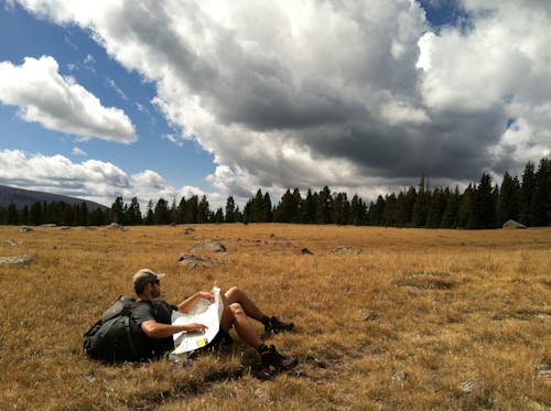 Man in Black Shirt With Black Backpack Lying on Brown Grass Photo