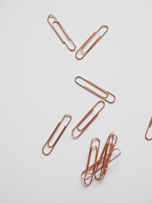 Rose gold paper clips on a pale desk, by Jess Bailey Designs on Pexels