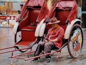 A Man in Red Jacket and Hat Sitting on a Carriage Parked on the Street