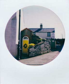 Retro photograph of a quaint village house with a vibrant yellow door and rustic stone walls.