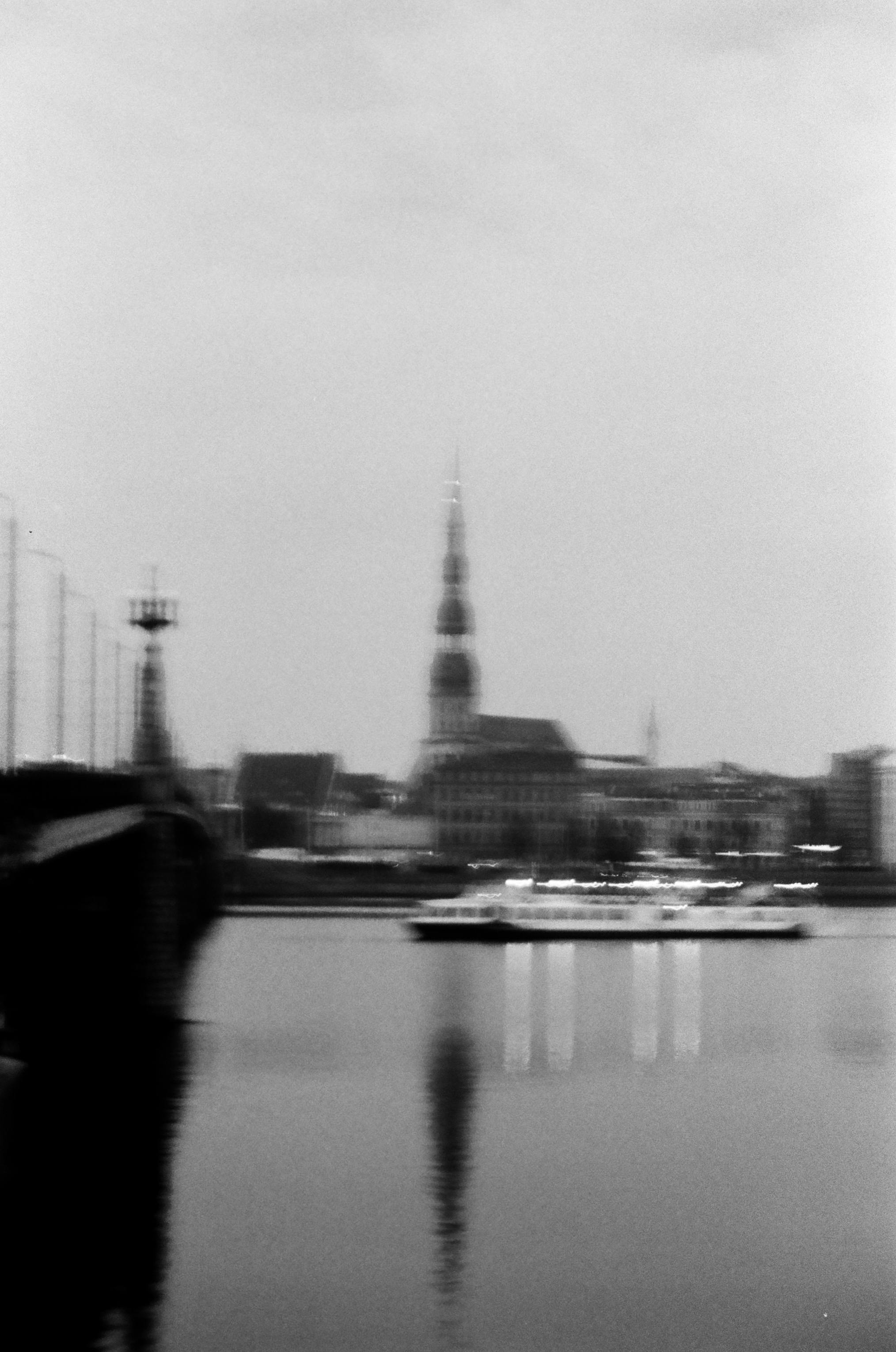 Abstract cityscape in black and white with water reflection, featuring a spire and bridge.