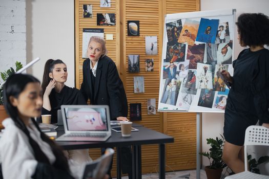 Diverse team of professionals in a collaborative workspace discussing creative ideas with visual references.