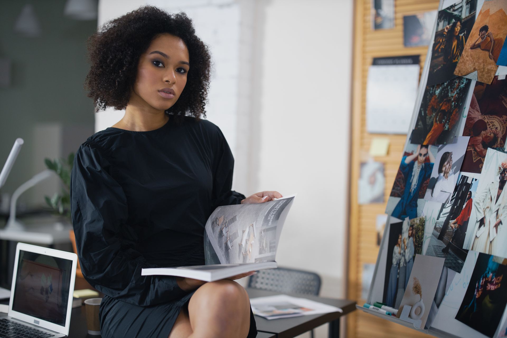 A Woman in Black Dress Sitting while Holding a Magazine