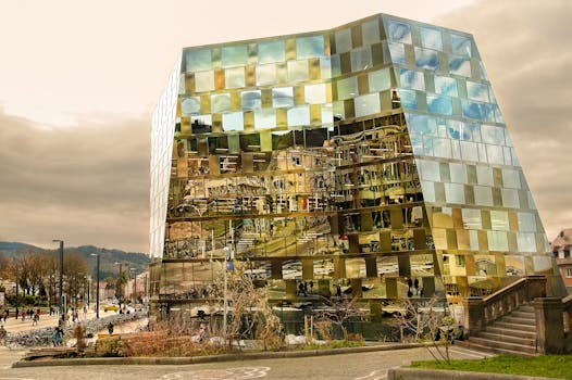 一座现代玻璃建筑倒映出城市环境和多云的天空