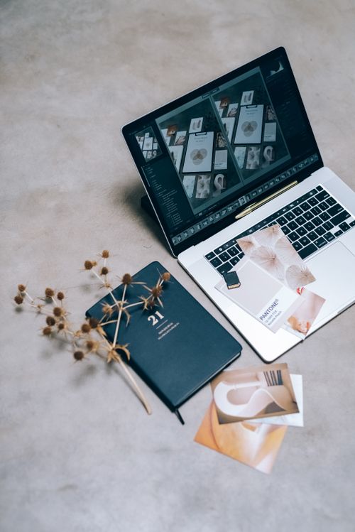 Free A high-angle shot of a creative workspace featuring a laptop, planner, and dried flowers on a flat surface. Stock Photo