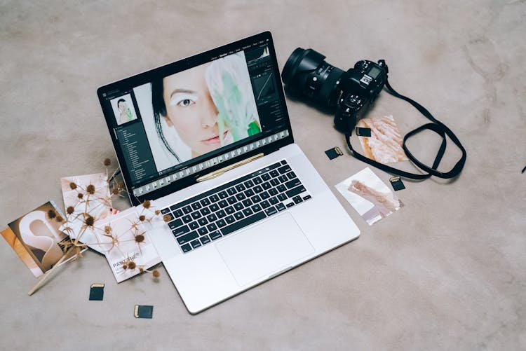 A Laptop Beside A Black Camera