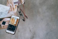 A Mobile Phone Near the Eyeglasses on a Concrete Surface